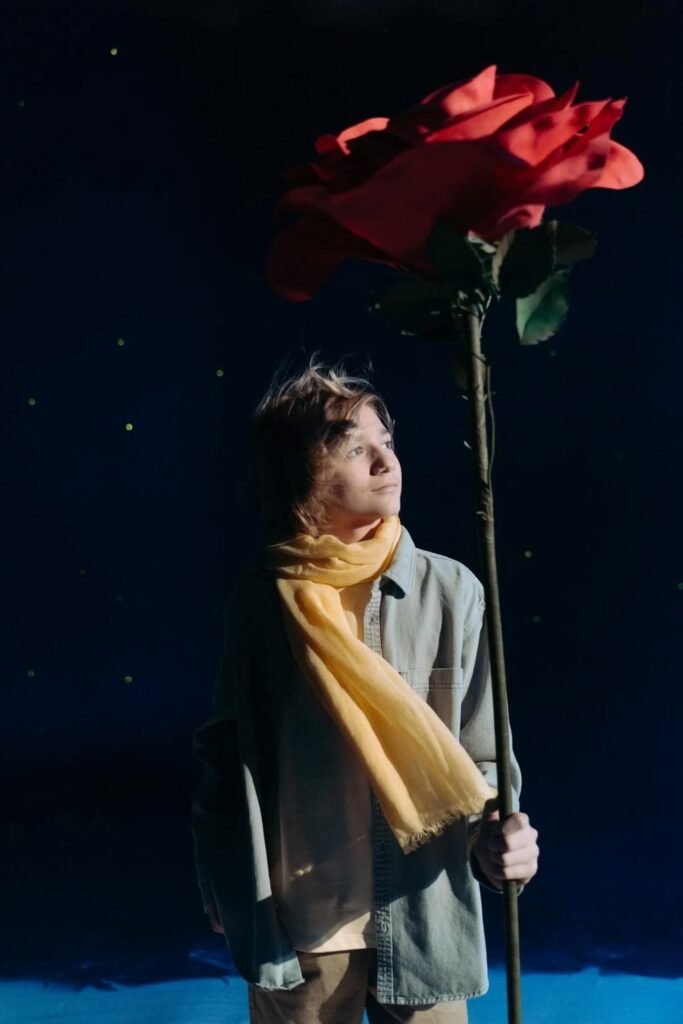 boy with yellow scarf holding a red flower 7182065
